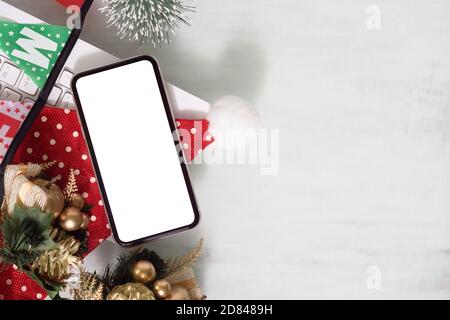 Smartphone con schermo bianco bianco mockup sulla scrivania dell'ufficio domestico con tastiera del computer su sfondo bianco per Natale e Capodanno, vista dall'alto piatta con Foto Stock