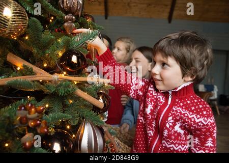 Felice giovane famiglia con i bambini decorare l'albero di Natale Foto Stock