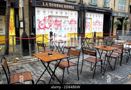 Tavoli vuoti e sedie fuori un ristorante che sembra sia chiuso. Bar e ristoranti in difficoltà a Londra saranno a crocevia alla fine di questa settimana. Sono pochi giorni prima della fine del programma di chiusure di strade a Soho e Covent Garden che ha permesso a ristoranti e bar di mettere tavoli per le strade per la prima volta. Soho è stato trasformato in un quartiere di ristorazione all'aperto, ma con l'avvicinarsi dell'inverno, le strade nel freddo e la pioggia sono praticamente vuote e con la prospettiva di un ulteriore blocco molte imprese che hanno cercato così difficile fare, sembrano essere fo Foto Stock