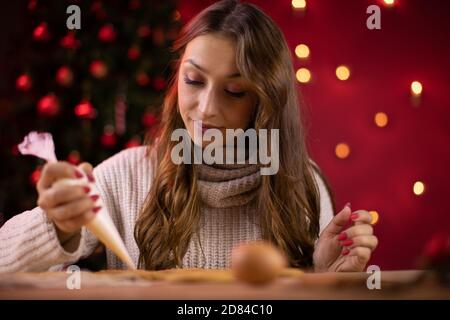 Concetto tradizionalista. Bella bruna giovane donna glacing Natale pan di zenzero Foto Stock