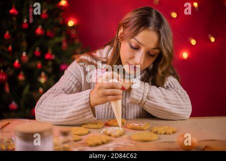 Concetto tradizionalista. Bella bruna giovane donna glacing Natale pan di zenzero Foto Stock