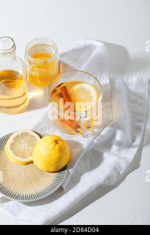 Bevande calde Toddy cocktail con limone, miele e cannella bastone in vetro su sfondo bianco. Bevanda invernale speziata Foto Stock