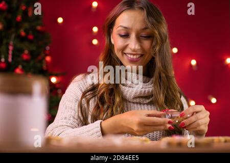 Concetto tradizionalista. Giovane donna che decora i biscotti di pan di zenzero di Natale Foto Stock