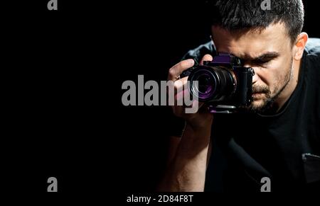 La persona è in possesso di una fotocamera ed è impostata per scattare. Il fotografo guarda nel mirino della fotocamera e scatta foto. L'oggetto su una b nera Foto Stock