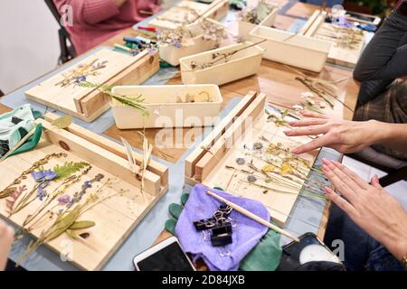 Una donna presenta una composizione. Master class sulla creazione di cornici con Herbarium in tecnica tiffany in vetro colorato. Erbario di diverso essiccato Foto Stock