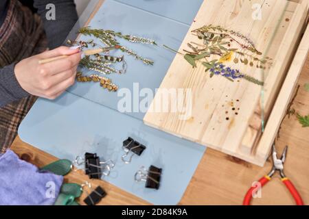 Una donna presenta una composizione. Master class sulla creazione di cornici con Herbarium in tecnica tiffany in vetro colorato. Erbario di diverso essiccato Foto Stock