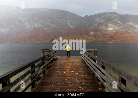 Donna in piedi sul molo di legno sul lago di Bohinj in autunno, sloveno parco nazionale Triglav Slovenia Foto Stock