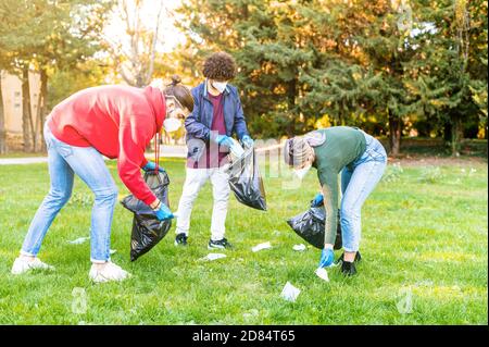 Volontari sta raccogliendo rifiuti di rifiuti con sacchetto di spazzatura, medico maschere nel parco,problema di lettering la maschera facciale durante covid-19 Quarantena - C Foto Stock