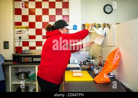 Netherton, West Midlands, Regno Unito. 27 ottobre 2020. Sarah Peniket-Aldridge prepara pasti da asporto nel suo bar - Netherton Cafe - nel Black Country, West Midlands, per i bambini durante il semestre scolastico. "Abbiamo inviato decine di pasti caldi per i bambini affamati. Forniamo anche quelli che isolano da Covid e alcune persone non possono pagare fino a quando non ottengono il loro credito universale o salari. Ma ottengono il loro cibo e li lasciamo pagare quando possono", dice. "Non lascerò che nessuno vada affamato." Netherton, a Sandwell, è in alto allerta, ed è una delle zone più povere dell'Inghilterra. Foto Stock