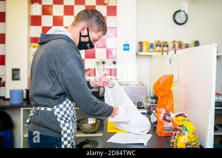 Netherton, West Midlands, Regno Unito. 27 ottobre 2020. Sarah Peniket-Aldridge prepara pasti da asporto nel suo bar - Netherton Cafe - nel Black Country, West Midlands, per i bambini durante il semestre scolastico. "Abbiamo inviato decine di pasti caldi per i bambini affamati. Forniamo anche quelli che isolano da Covid e alcune persone non possono pagare fino a quando non ottengono il loro credito universale o salari. Ma ottengono il loro cibo e li lasciamo pagare quando possono", dice. "Non lascerò che nessuno vada affamato." Netherton, a Sandwell, è in alto allerta, ed è una delle zone più povere dell'Inghilterra. Foto Stock