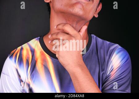 Giovane uomo con gola irritata su fondo nero Foto Stock