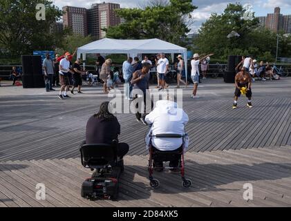 Due persone disabili guardano i ballerini sul lungomare di Coney Island, Brooklyn, New York, USA. Foto Stock