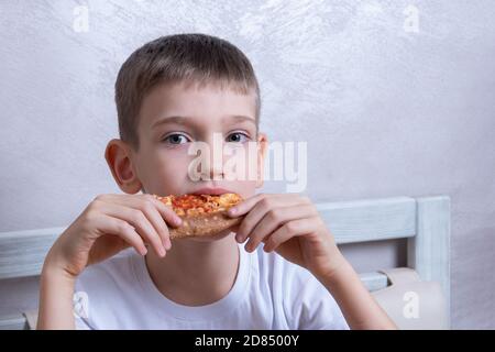 Ragazzo carino che mangia una fetta di pepperoni e pizza al formaggio, primo piano, copia spazio. Concetto di cibo malsano Foto Stock