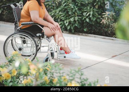 Sovrappeso e obesità donna seduta su sedia a rotelle e tenendo il ginocchio in dolore, causa di infiammazione del suo ginocchio a ricevere troppo peso, Conce Foto Stock