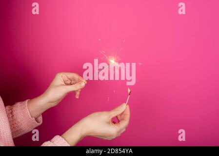 Primo piano di mani donna che tengono scintilla. Buon concetto di anno nuovo. La ragazza mette il fuoco a sparkler Foto Stock