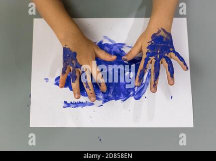 le mani dei bambini sono dipinte in vernice blu. educazione, concetto scolastico. messa a fuoco morbida Foto Stock