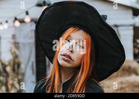 una ragazza in un costume di strega che si diverte ad un Festa di Halloween sul portico decorato Foto Stock