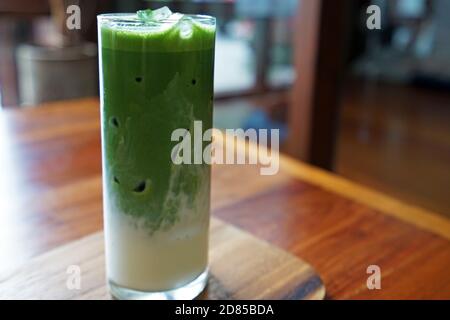 Primo piano bicchiere di latte di tè verde Iced Matcha tavola in legno Foto Stock