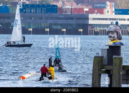 27 ottobre 2020, Meclemburgo-Pomerania occidentale, Wismar: Il nuovo albero per la replica della nave a vela del Poeler Kogge 'Wissemara' è trainato nel porto da due barche gonfiabili. Per ragioni di costo, l'associazione di sviluppo di Poeler Kogge sta trasportando il tronco lungo 32 metri lungo la rotta marittima di undici chilometri da un cantiere navale sull'isola di Poel al porto di Wismar, galleggiando in acqua. Il tronco di un abete Douglas di 140 anni è stato sradicato, piallato liscio e segato a lunghezza dal luglio 2020. Per la prossima stagione, il nuovo montante sarà poi montato nei prossimi mesi su un Foto Stock