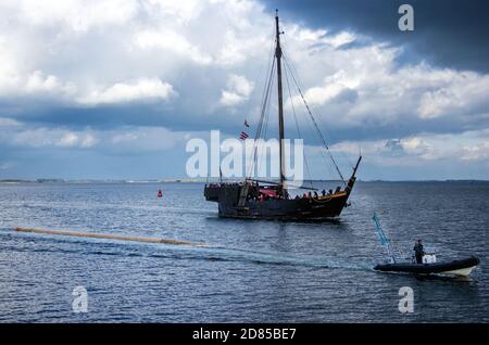 27 ottobre 2020, Meclemburgo-Pomerania occidentale, Wismar: Accompagnato dalla cog 'Wissemara' di Poel, il nuovo albero per la replica della nave a vela è trainato nel porto da due barche gonfiabili. Per ragioni di costo, l'associazione di sviluppo di Poeler Kogge sta trasportando il tronco lungo 32 metri lungo la rotta marittima di undici chilometri da un cantiere navale sull'isola di Poel al porto di Wismar, galleggiando in acqua. Il tronco di un abete Douglas di 140 anni è stato sradicato, piallato liscio e segato a lunghezza dal luglio 2020. Per la prossima stagione, il nuovo montante sarà montato sopra il prossimo f Foto Stock