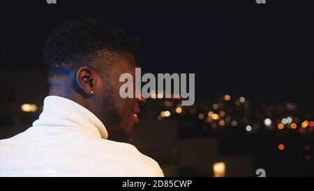 colpo di testa. Giovane uomo nero afroamericano in piedi sul balcone e guardando a distanza. Tempo di silenzio durante il blocco. Foto di alta qualità Foto Stock