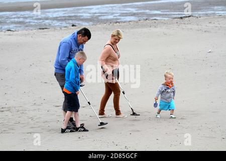 Girvan, Ayrshire, Scozia, Regno Unito. Una famiglia sulla spiaggia metal detecting in cerca di tesoro, sullo sfondo può essere visto l'iconica Ailsa Craig Foto Stock