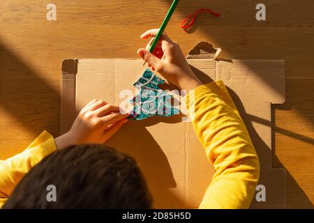 Il ragazzo preschooler disegna o fa mestieri su un tema di Natale, colorazione, attività per i bambini a casa Foto Stock