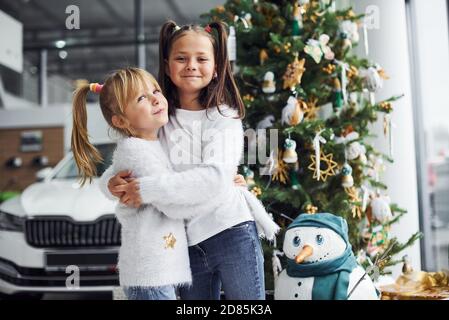 Due bambine carine in piedi vicino auto e albero di natale a nuovo anno Foto Stock