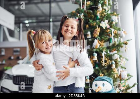 Due bambine carine in piedi vicino auto e albero di natale a nuovo anno Foto Stock