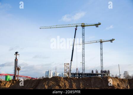 Luffing idraulico braccio gru a torre e i lavoratori di calcestruzzo colato in fondazione. Colata di cemento in cassaforma di costruzione al cantiere. T Foto Stock