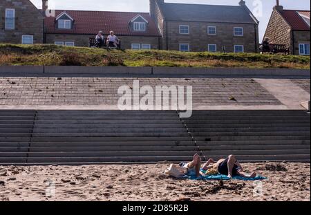 Persone che prendono il sole sulla spiaggia, Whitby, Inghilterra, Regno Unito Foto Stock