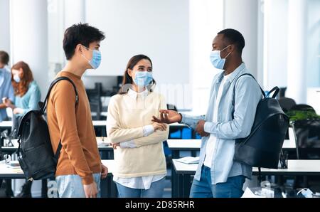 Studenti internazionali che indossano maschere mediche e parlano Foto Stock