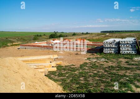 La costruzione della fondazione per la costruzione in campo su sfondo cielo blu. Anno paesaggio al giorno solare Foto Stock