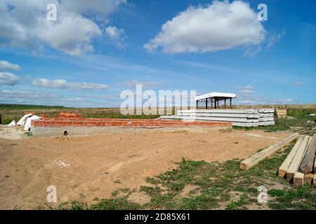 La costruzione della fondazione per la costruzione in campo su sfondo cielo blu. Anno paesaggio al giorno solare Foto Stock