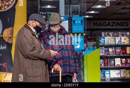 Due uomini che indossano maschere al di fuori dell'edicola, Norwich, Norfolk, UK Foto Stock