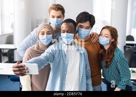 Studenti internazionali che indossano maschere mediche che prendono selfie Foto Stock