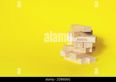 17 giugno. Giorno 17 del mese, data del calendario. Blocchi di legno ripiegati nella torre con mese e giorno su sfondo giallo, con spazio di copia. Mese estivo, Foto Stock