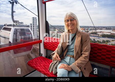 Regno Unito, Londra, North Greenwich, servizio di funivia Emirates Air Line sul Tamigi, passeggero senior in gondola Foto Stock