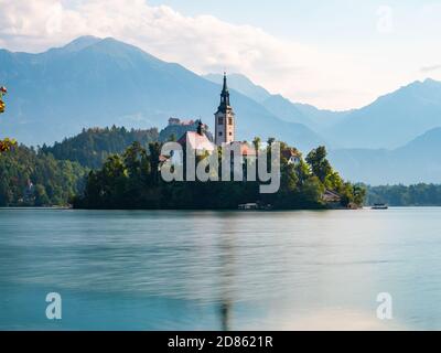 Lunga esposizione del lago Bled Slovenia, mattina presto, giorno nuvoloso, riflessi in acqua, vista laterale dell'isola e delle montagne in primo piano Foto Stock