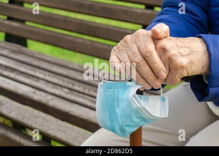 Vecchia signora che tiene il bastone nel parco. Donna anziana che tiene il bastone da passeggio all'aperto. Mani di pensionato su canna da vicino Foto Stock