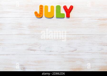 Lettere di legno scritte mese di luglio su sfondo vintage. Iscrizione luglio con spazio copia. Vista dall'alto. Mockup per gli eventi del calendario. Una serie di 12 mesi Foto Stock