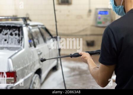 coronavirus pulizia della macchina, lavando la carrozzeria con un pulitore da soluzione di sapone. Il lavoro di tecnici automatici durante il periodo di quarantena COV Foto Stock