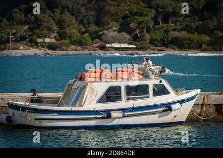 Piccolo motoscafo bianco e blu con cintura di sicurezza arancione in cima, ormeggiato nel porto di Portovenere o Porto Venere. La Spezia, Liguria, Italia, Europa Foto Stock