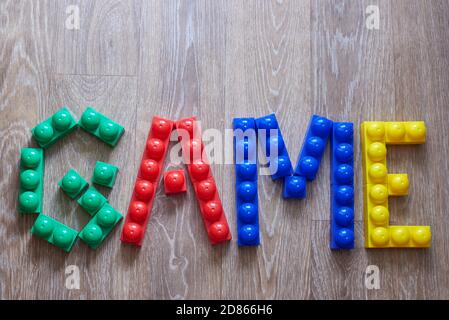 La parola gioco ha fatto uscire da grandi pezzi di costruttore su uno sfondo di legno. Foto Stock