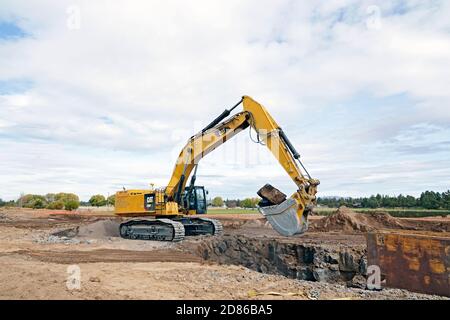 Un trattore grande e movimento terra in un cantiere a Bend, Oregon, sposta i massi in un frantumatore di rocce per fare ghiaia. Il cantiere è per Foto Stock