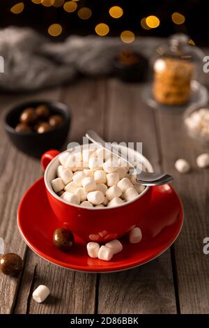 Cioccolata calda con marshmallow in tazza rossa su tavolo di legno Foto Stock
