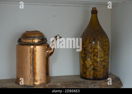 Splendida vista ravvicinata dei dettagli della decorazione d'interni d'epoca retrò. Teiera Old cooper e bottiglia di vetro riempita con tappi per bottiglie. Foto Stock