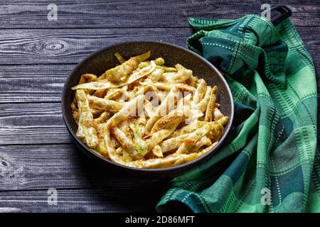 Piatto vegetariano: Fagioli di cera d'oro francesi con aglio e prezzemolo ricoperti di pangrattato e fritti su una padella su fondo di legno scuro, vista dall'alto, Foto Stock