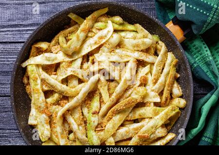 Piatto vegetariano: Fagioli di cera d'oro francesi con aglio e prezzemolo ricoperti di pangrattato e fritti su una padella su fondo di legno scuro, vista dall'alto, Foto Stock