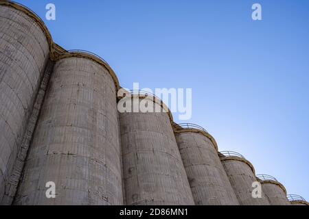 Impianti industriali silos di calcestruzzo per stoccaggio in bulk. Grande struttura in fabbrica su sfondo blu del cielo, vista ad angolo basso Foto Stock